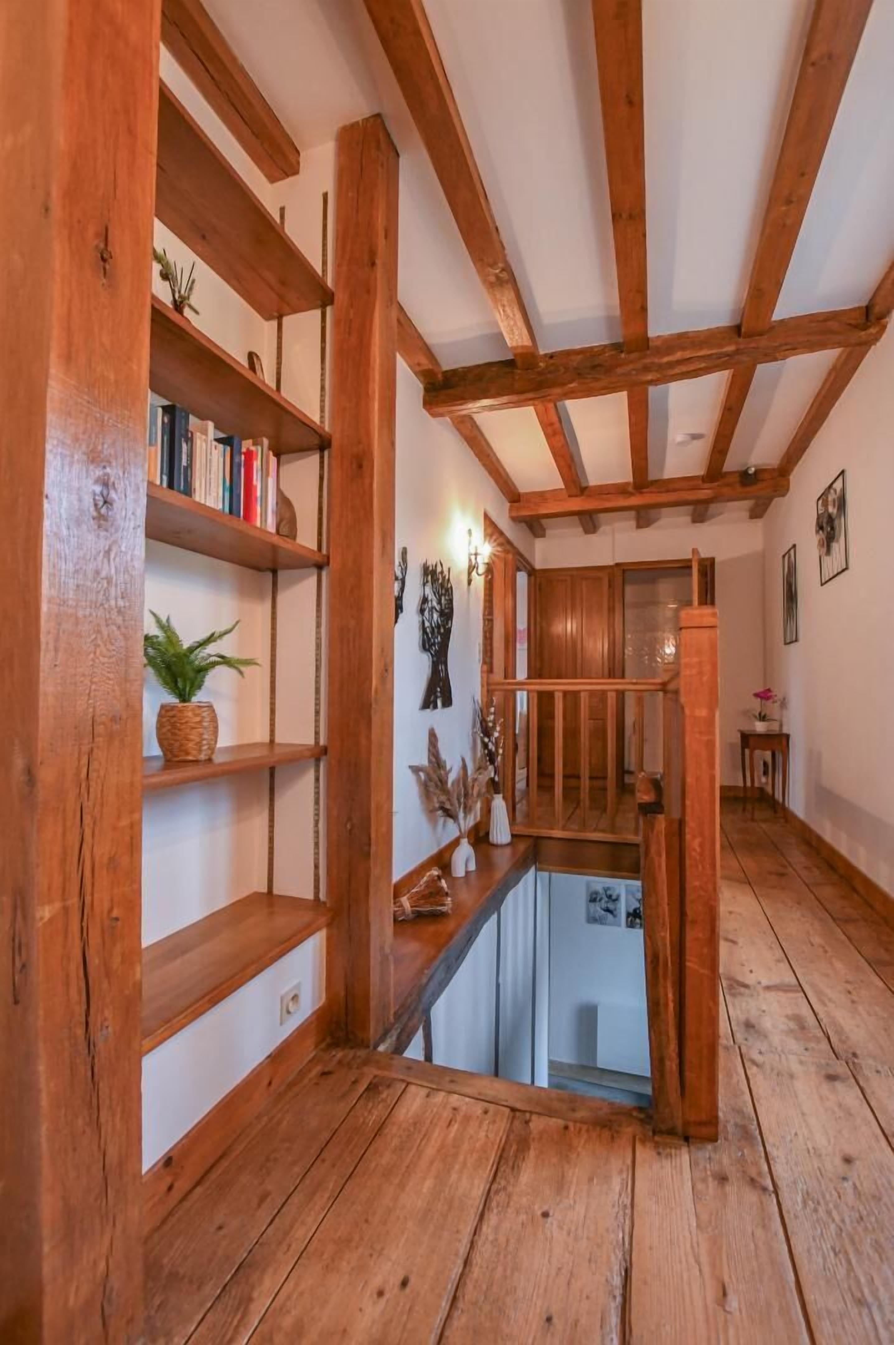 Ein Holzinnenraum mit freiliegenden Balken, einer Treppe und einem kleinen Tisch mit einer Vase.
