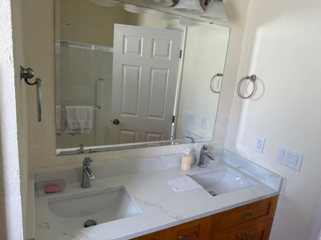 Un baño con un lavamanos blanco, un espejo y una puerta.