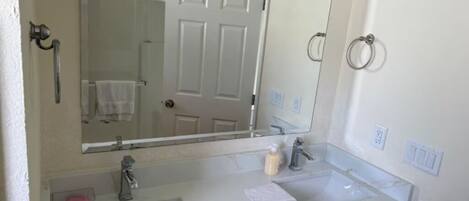 Un baño con un lavamanos blanco, un espejo y una puerta.