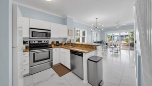 A modern kitchen with white cabinets, stainless steel appliances, and a granite countertop. - 7026 Waterfront Duck Key Villa - Sleeps 6 (Marathon)