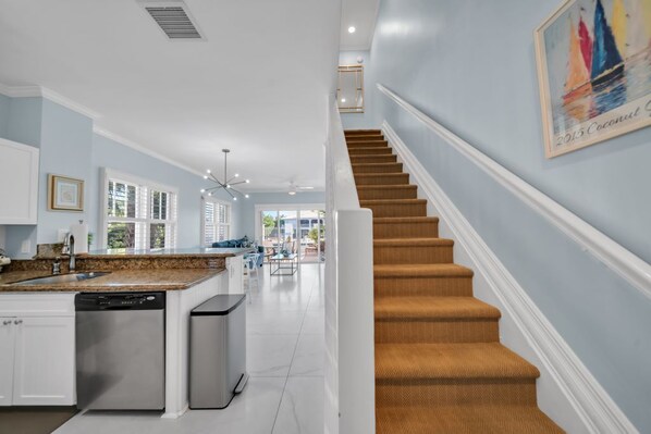 A modern kitchen with white cabinetry, a granite countertop, and stainless steel appliances. - 7026 Waterfront Duck Key Villa - Sleeps 6 (Marathon)
