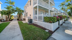 A two-story house with a porch, a small garden, and a pathway leading to the entrance. - 7026 Waterfront Duck Key Villa - Sleeps 6 (Marathon)