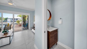 A modern bathroom with a white vanity, a wooden cabinet, and a curved mirror. - 7026 Waterfront Duck Key Villa - Sleeps 6 (Marathon)