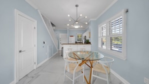 A modern kitchen with a glass dining table, white cabinetry, and a staircase leading to another level. - 7026 Waterfront Duck Key Villa - Sleeps 6 (Marathon)