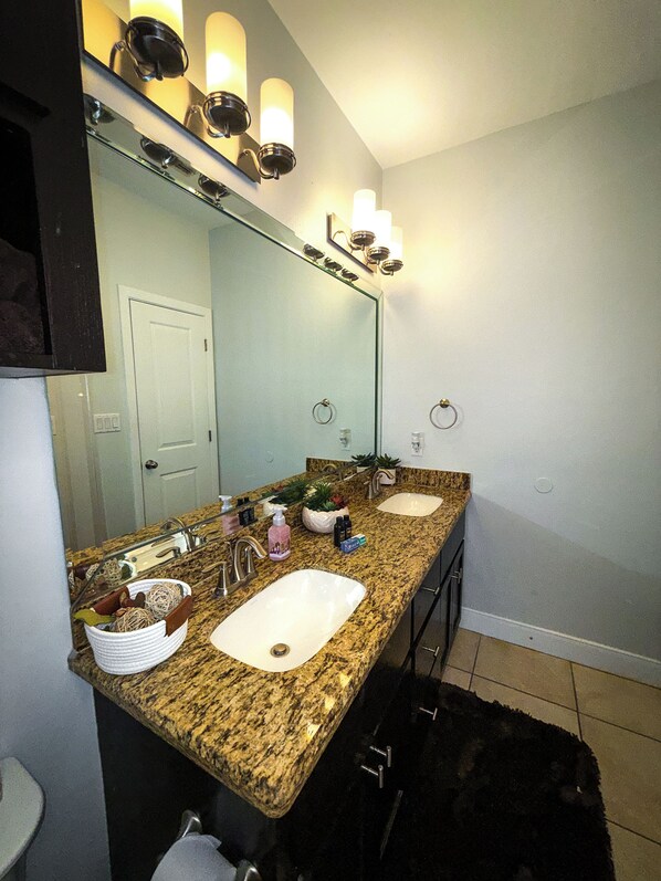 A bathroom with two sinks, a large mirror, and wall sconces.
