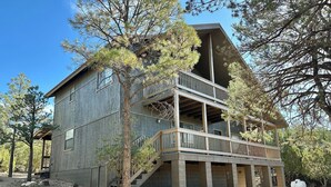A two-story cabin with a balcony, surrounded by trees and a dry landscape. - Wild Aspen Ridge | Space to Gather, Room to Unwind (Heber-Overgaard)