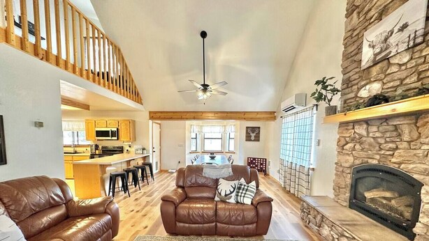 A spacious living room with a leather sofa, a fireplace, and a kitchen in the background. - Wild Aspen Ridge | Space to Gather, Room to Unwind (Heber-Overgaard)