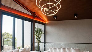 A modern living room with a wooden ceiling, a large sofa set, a dining table, and a hanging light fixture. - Delta na Mata - Sto Amaro da Imperatriz (Santo Amaro da Imperatriz)