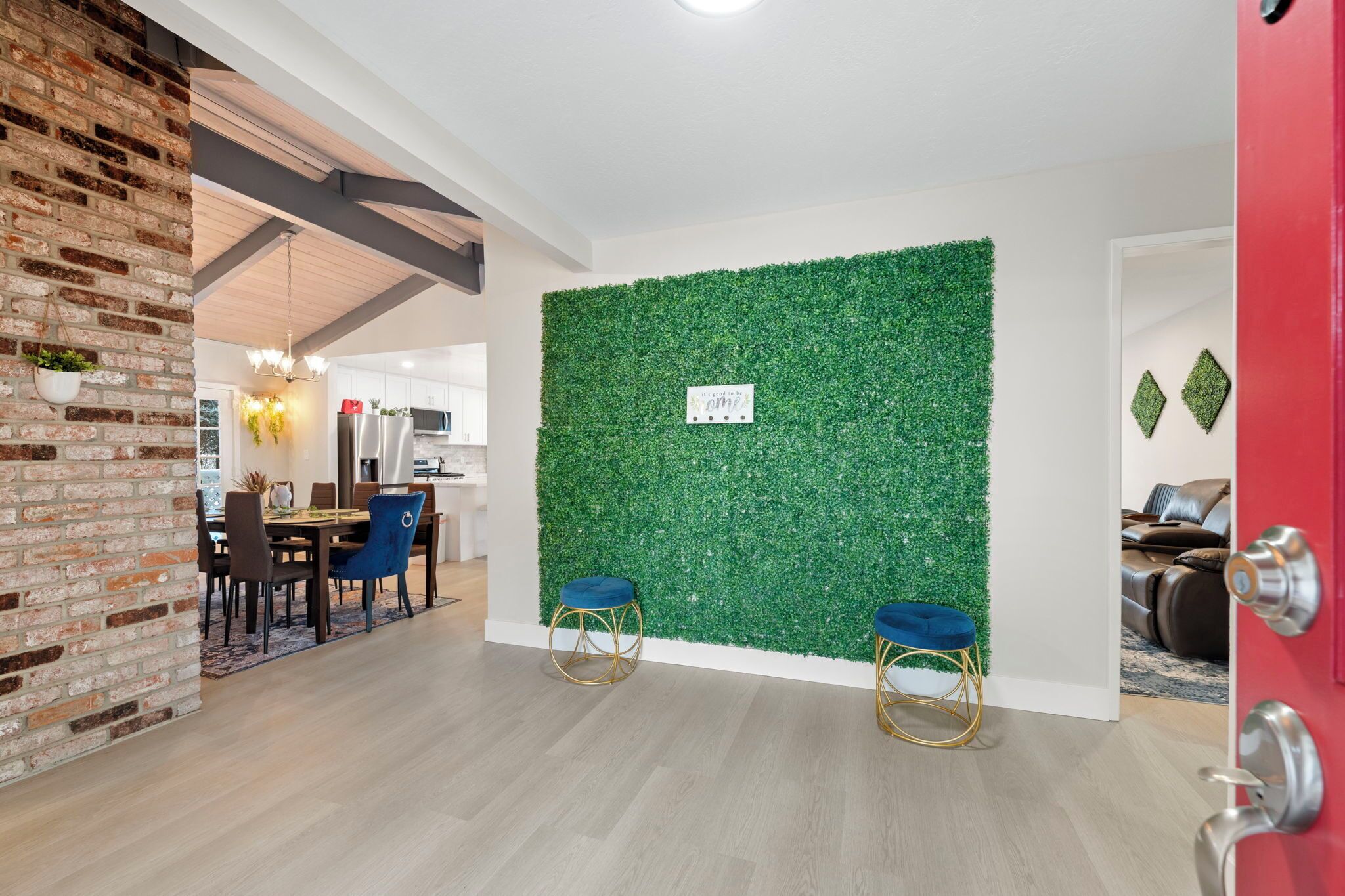 A modern interior with a brick wall, a green wall with a sign, and a dining area with chairs and a table.