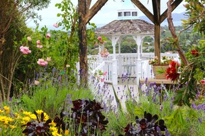 A gazebo surrounded by lush greenery and flowers. - Cherry Villa (Paraparaumu)