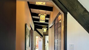 A hallway with a sloped ceiling, framed pictures on the walls, and a door with a glass panel. - Cherry Villa (Paraparaumu)