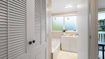 Une salle de bain moderne avec une baignoire, un lavabo et une fenêtre.