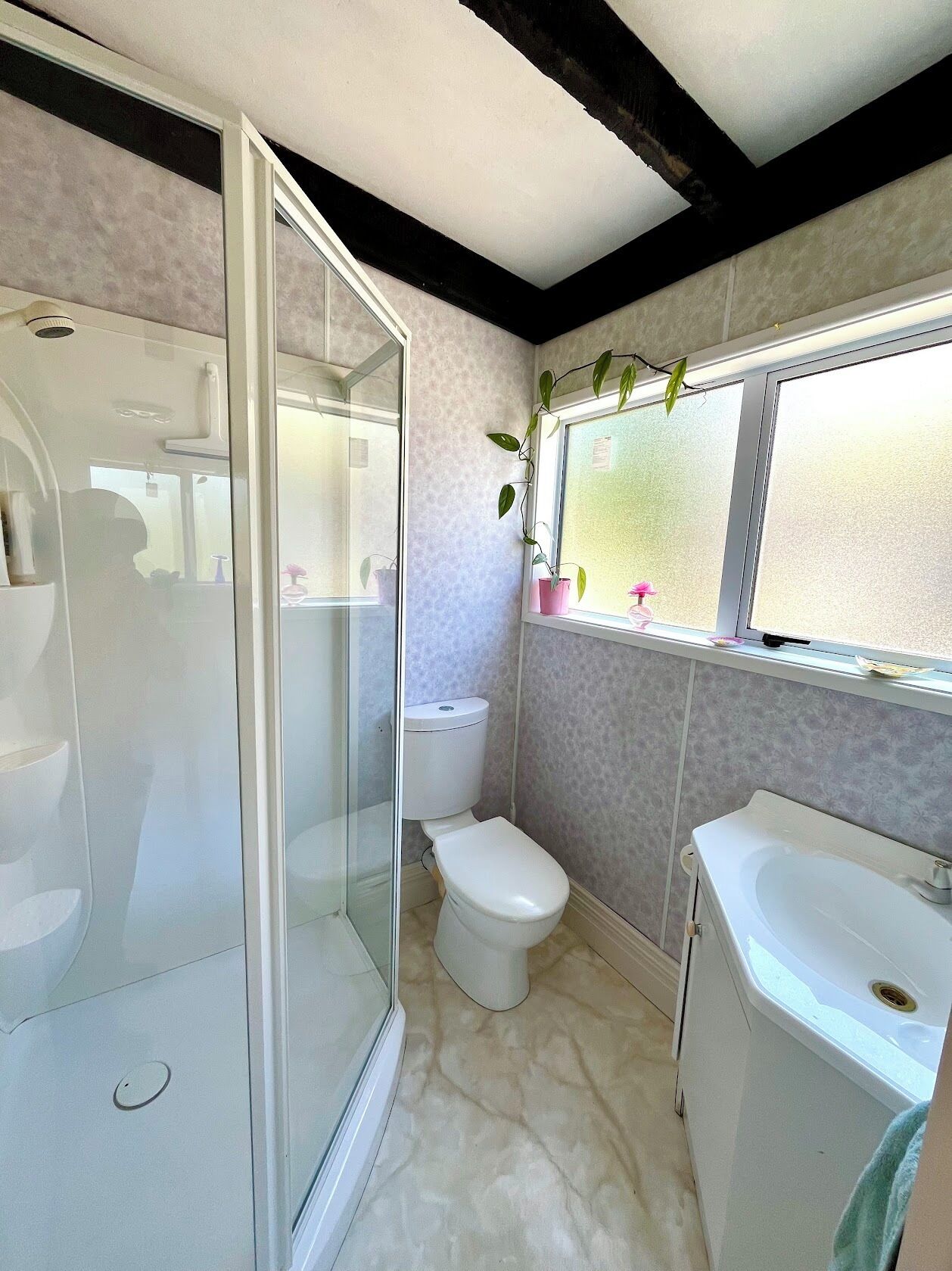 Een badkamer met douche, toilet en wastafel.