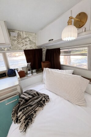 Un interior acogedor con una cama, una mesita de noche, una lámpara y una ventana con cortinas.