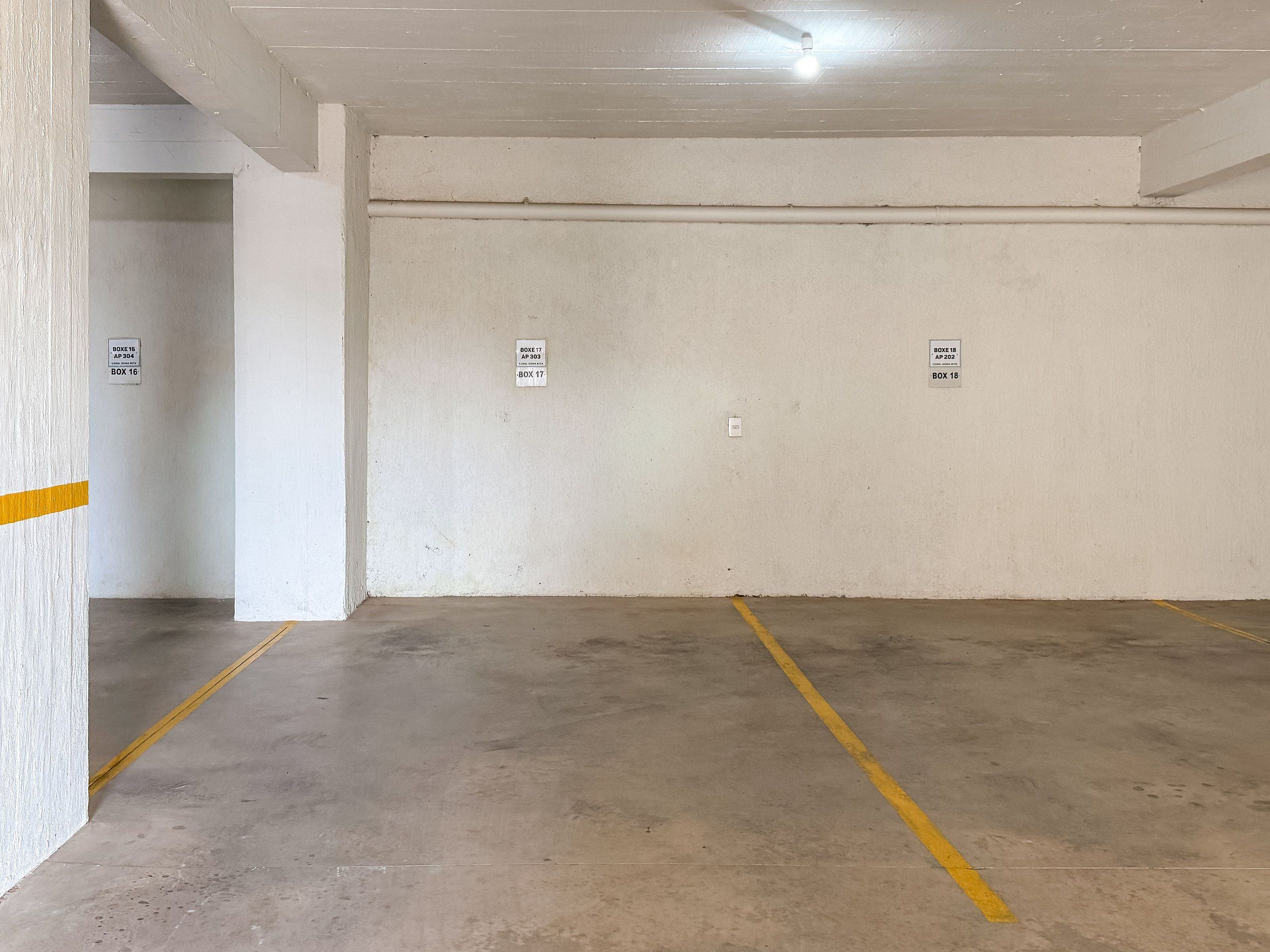Un parking souterrain aux murs en béton, avec des lignes jaunes délimitant les places et des panneaux indiquant les emplacements disponibles.