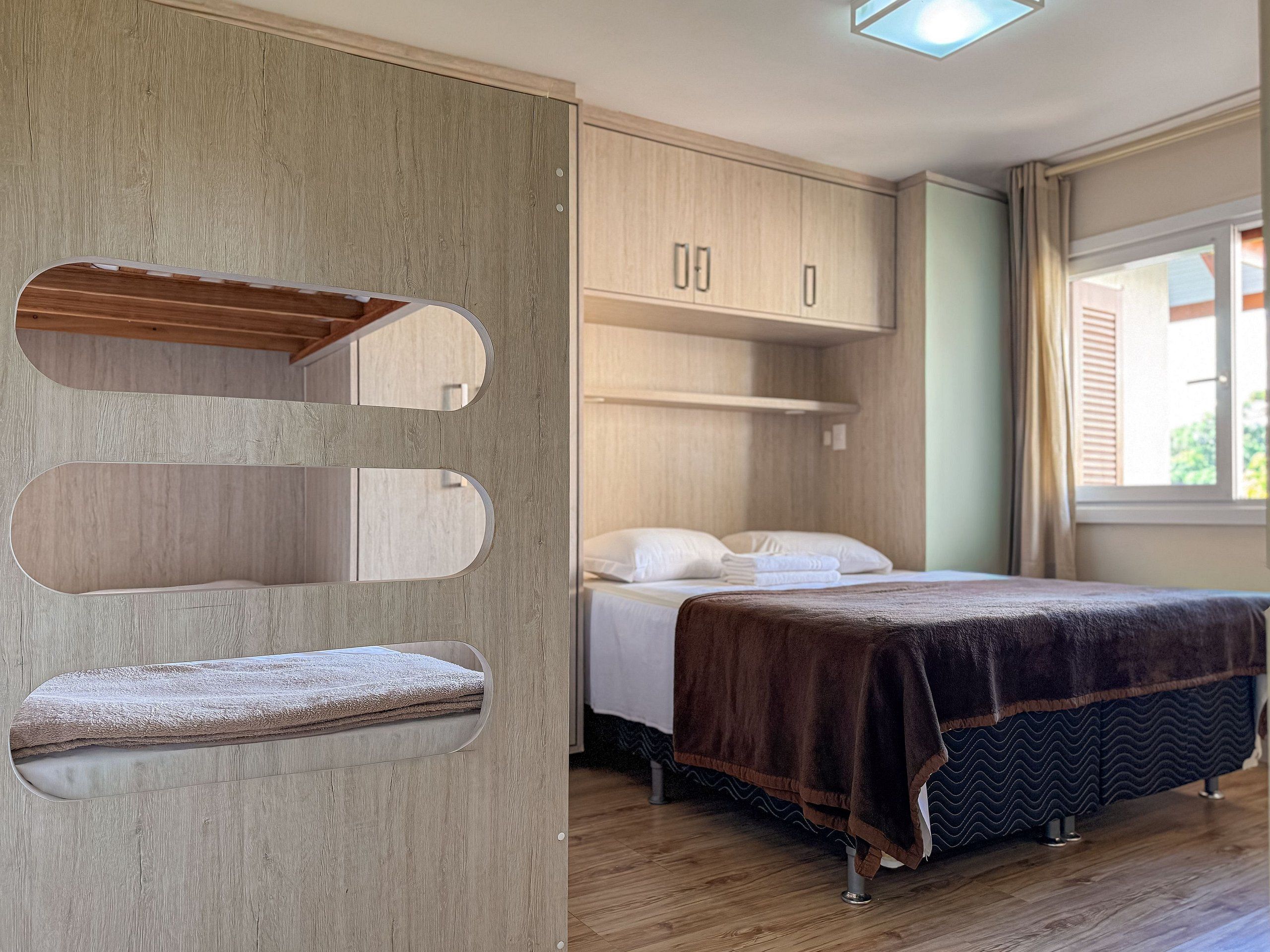 Un dormitorio con una cama, un armario de madera y un banco empotrado con espacio de almacenamiento.
