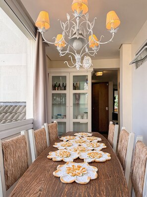 Une salle à manger avec une table en bois, des chaises blanches et un lustre.