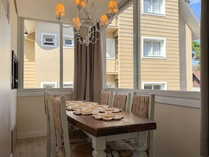 Una mesa de comedor con candelabro, cortinas y vistas a edificios cercanos.