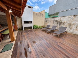Un patio al aire libre con piso de madera, una parrilla y zonas de estar.