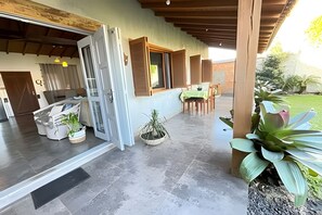 A spacious patio with a dining area, a covered entrance, and potted plants.