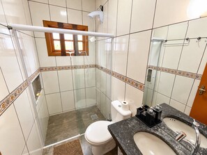 Un baño con cabina de ducha de vidrio, inodoro, lavabo con encimera de mármol y espejo.