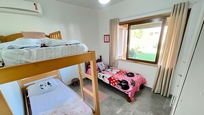 A room with bunk beds, a window with curtains, a small stool, and a framed picture on the wall. - Casa 2 Quartos - Centro - Xangri-Lá (Xangri-La)