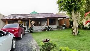 A house with a tiled roof, a paved driveway, and a well-maintained lawn. - Casa 2 Quartos - Centro - Xangri-Lá (Xangri-La)