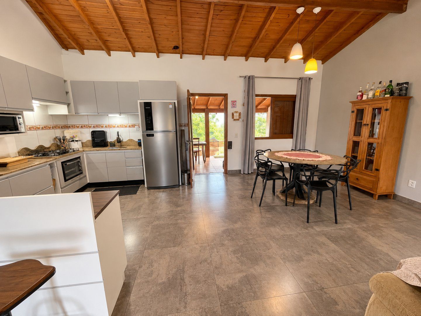 Uma cozinha moderna com forno embutido, geladeira e área de jantar com mesa redonda e cadeiras.