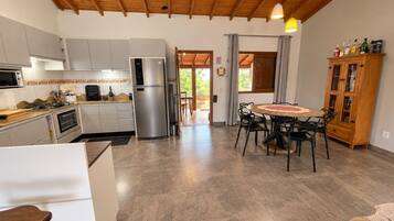 Uma cozinha moderna com forno embutido, geladeira e área de jantar com mesa redonda e cadeiras.