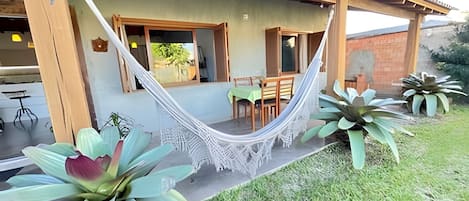 Ett hus med en inglasad veranda, en hängmatta och stora växter.