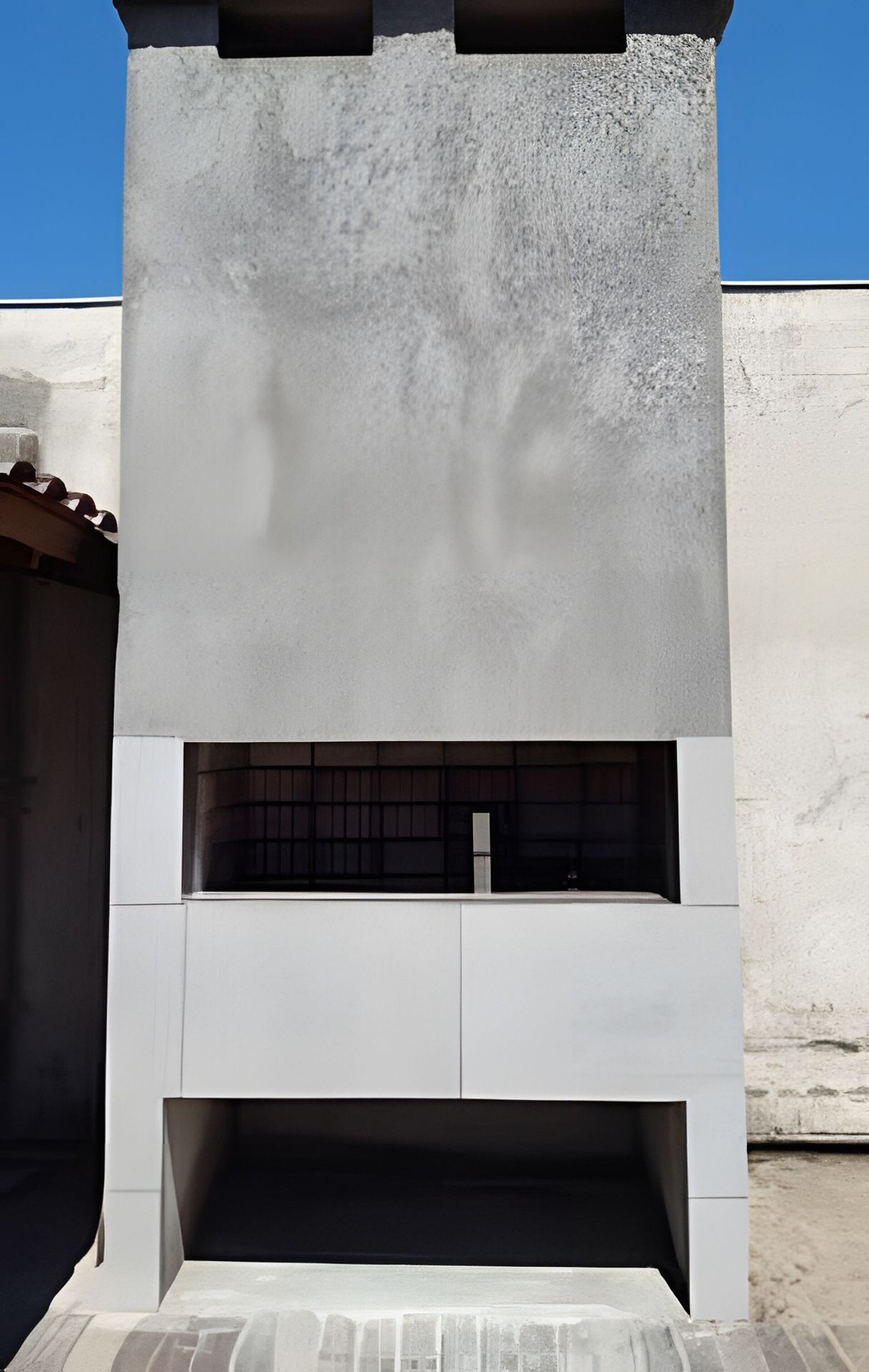Uma lareira ao ar livre moderna, com fachada de concreto e painel branco na base.