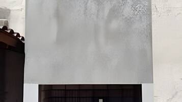 Uma lareira ao ar livre moderna, com fachada de concreto e painel branco na base.