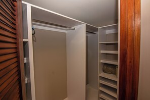 Ein begehbarer Kleiderschrank mit geöffneten Türen, der Regale und Kleiderstangen zeigt.