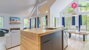 A modern kitchen with a wooden island, built-in appliances, and large windows offering a view of the outdoors.