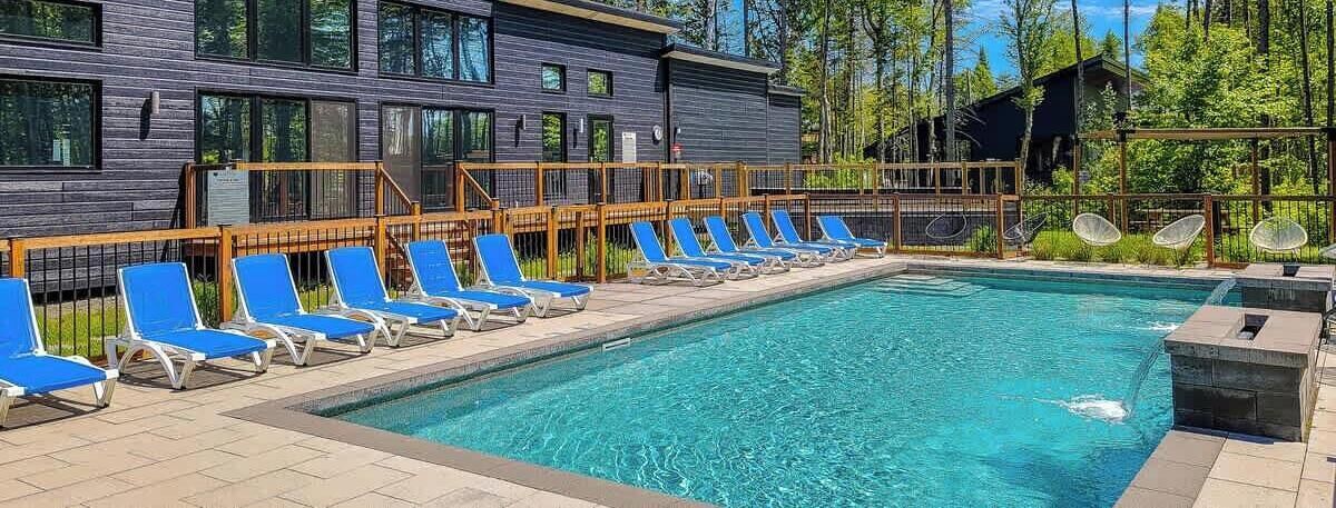 A swimming pool with blue lounge chairs and a wooden deck.