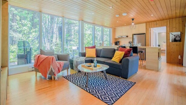 A spacious living room with a sofa, coffee table, and a view of the outdoors through large windows.