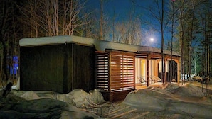 A cabin with a wooden exterior, a covered porch, and a chair outside.