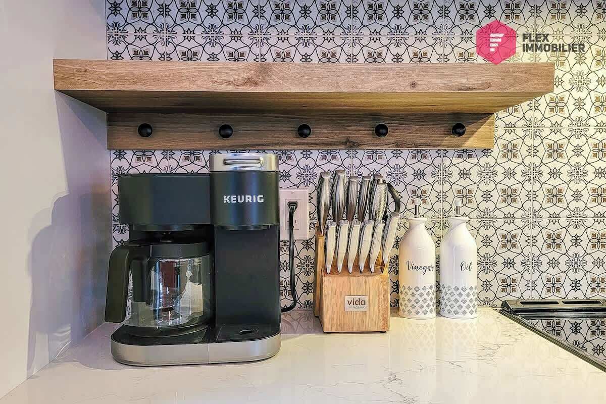 Ett köksutrymme med en Keurig-kaffemaskin, ett knivställ och flaskor med vinäger och olja på bänkskivan.