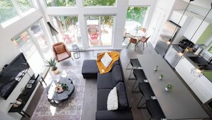 Un espacio habitable moderno de concepto abierto con sofá, mesa de comedor y área de cocina.