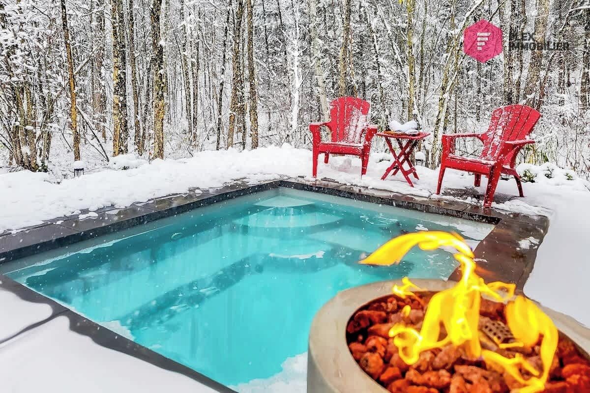 Una piscina con sedie rosse e un elemento decorativo a fuoco.