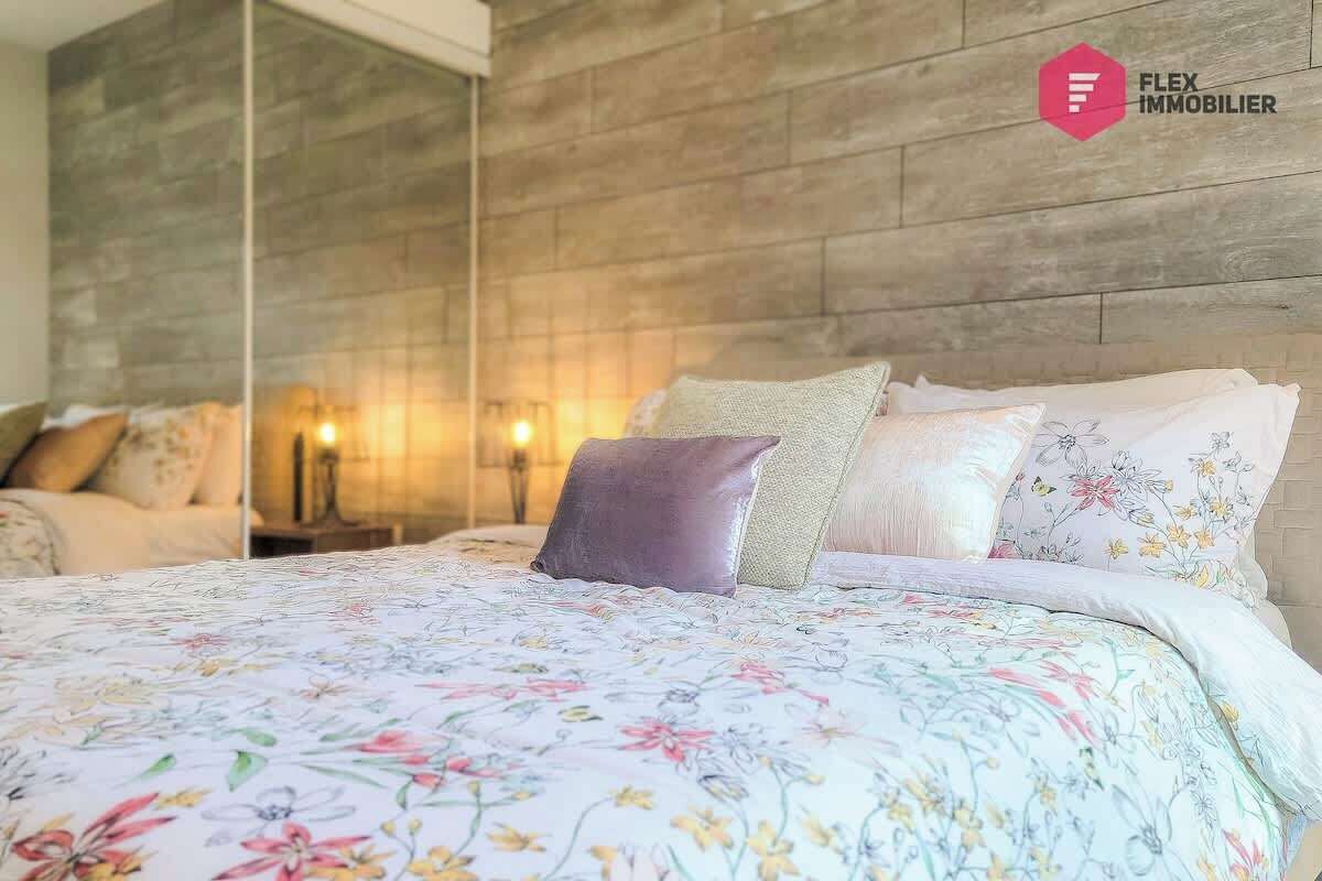 A bedroom with a wooden headboard, floral bedding, and a nightstand with a lamp.