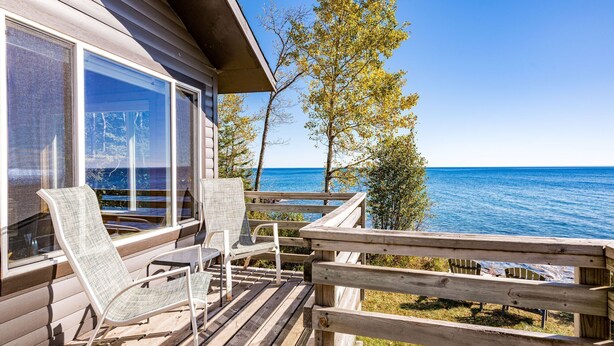 Une terrasse en bois avec deux chaises longues et une vue sur l’océan.