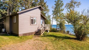Une cabane avec une terrasse et vue sur l’eau.