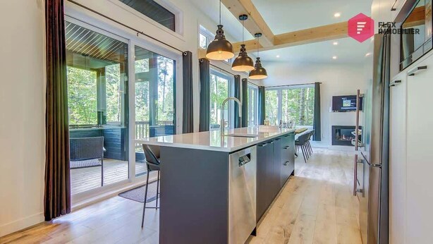 A modern kitchen with a central island, large windows, and pendant lighting. - The Sunny-Haus in Portneuf - Private hot tub, Pool (Pont-Rouge)