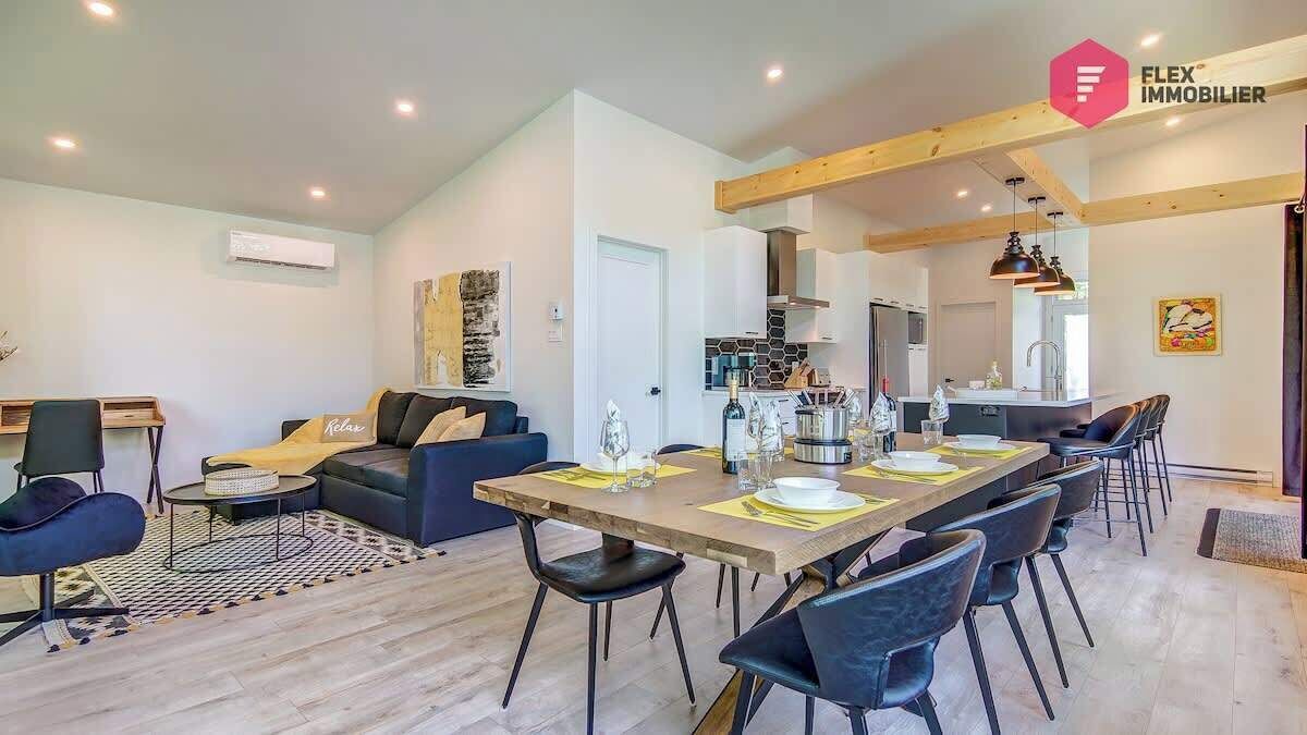 A modern living room with a dining area, featuring a sofa, a coffee table, and a dining table set for four.