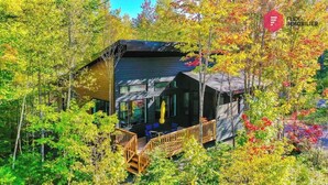 A modern cabin with a deck, surrounded by trees. - The Sunny-Haus in Portneuf - Private hot tub, Pool (Pont-Rouge)