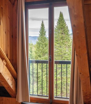Une pièce dotée d’une grande fenêtre, de murs en bois et d’un balcon agrémenté d’une balustrade.