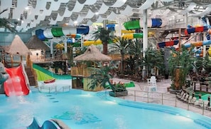 Et indendørs vandland med rutsjebaner, pools og dekorationer i trope-stil.