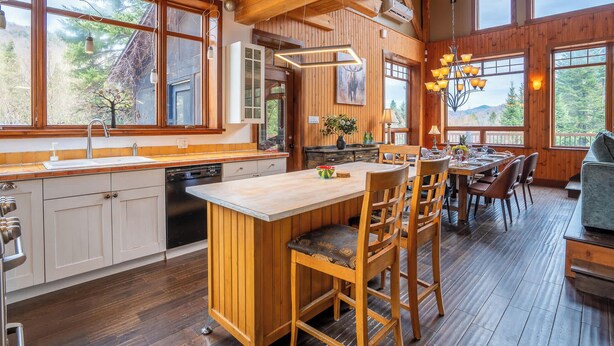 Una cocina amplia con armarios de madera, una isla central y un comedor con sillas y mesa de madera.