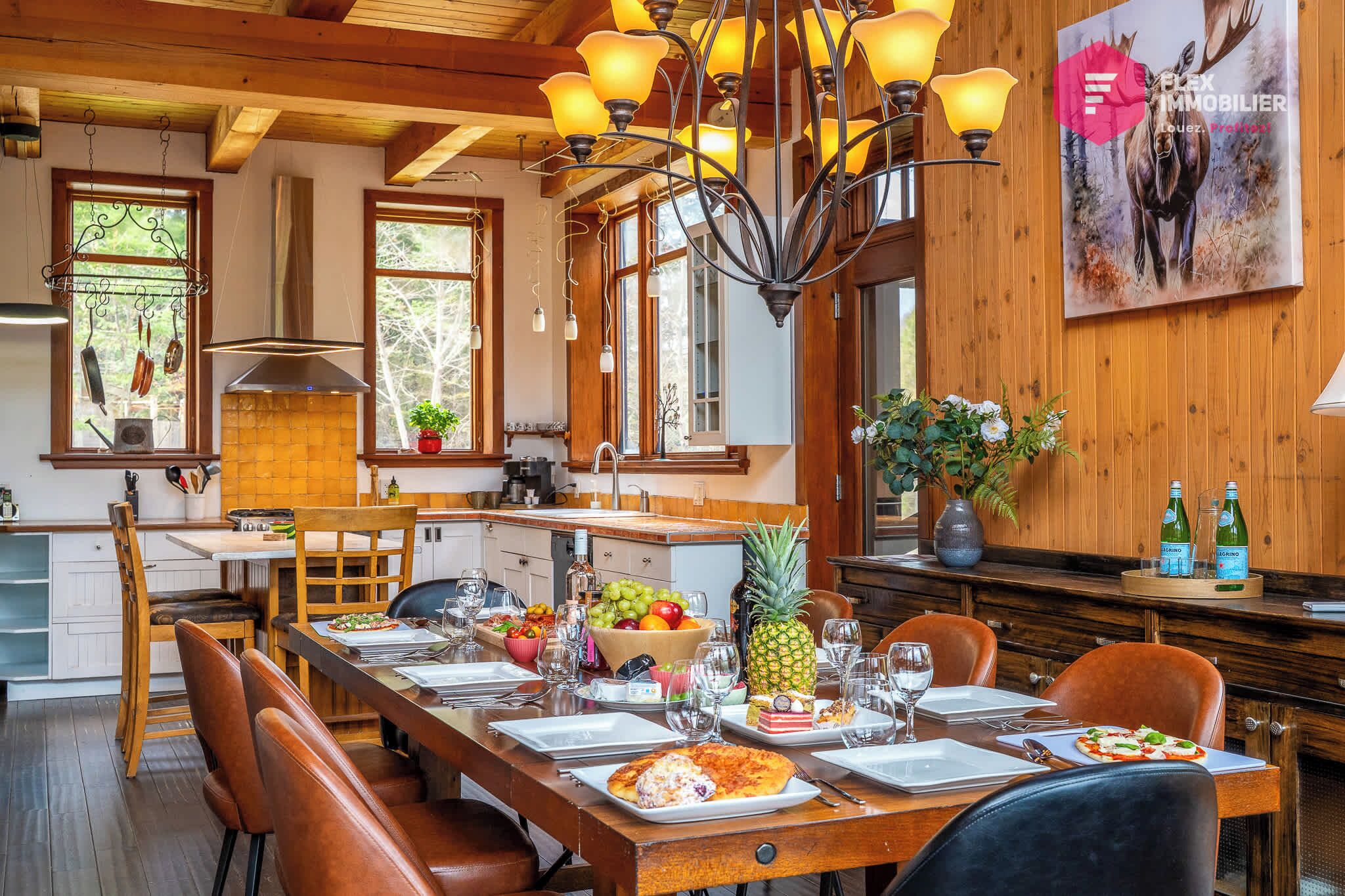 A dining area with a long wooden table set for a meal, surrounded by chairs.